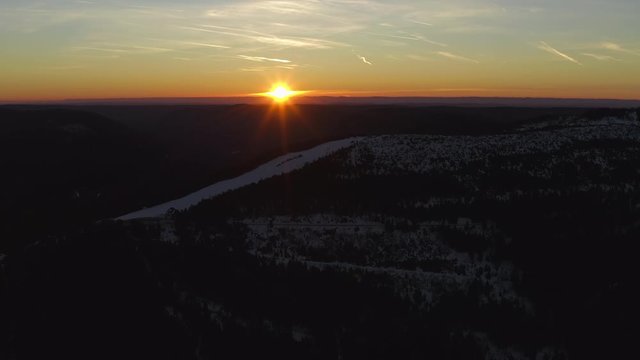 Sunrise over a ski run on a snowy black forest mountain Seibelskeckle on a clear morning in Winter.
