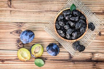 Fresh prunes in bowl on old table top view. Ripe plums on rustic board.