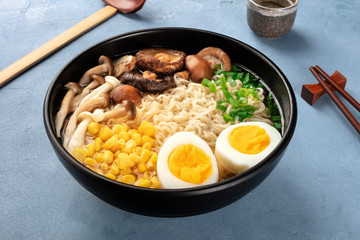 Ramen. Soba noodles with eggs, mushrooms, and vegetables, with sake, traditional wooden spoon, and chopsticks