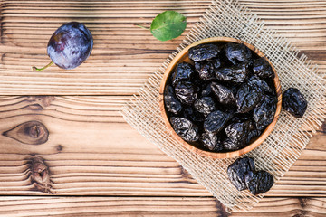 Fresh prunes in bowl on old table top view. Ripe plums on rustic board.