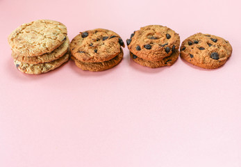 Many cookies are arranged horizontally on a pink background.