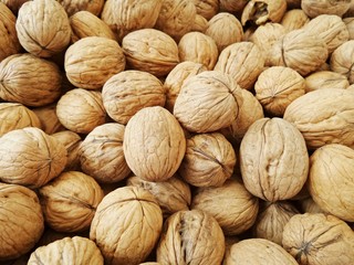 Inshell walnuts close-up. Brown walnuts on counter of bazaar or greengrocery. Selective focus image.