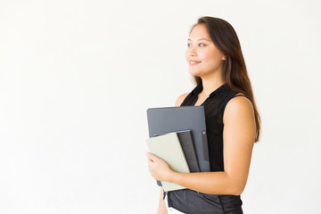 Obraz premium Happy young woman holding folder and books. Beautiful cheerful young female student holding folder and looking aside on white background. Education concept