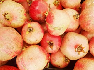 Bright red pomegranates close-up. Ripe juicy pomegranates on counter of bazaar or greengrocer. Selective focus image.