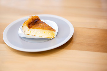 Cheesecake sliced in white dish on wooden table background