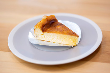 Homemade cheesecake sliced in white dish on wooden table background