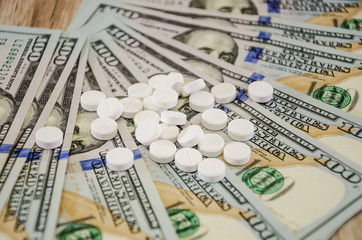 white pills on dollars, close up.