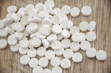 many white pills on a wooden background. Close-up.