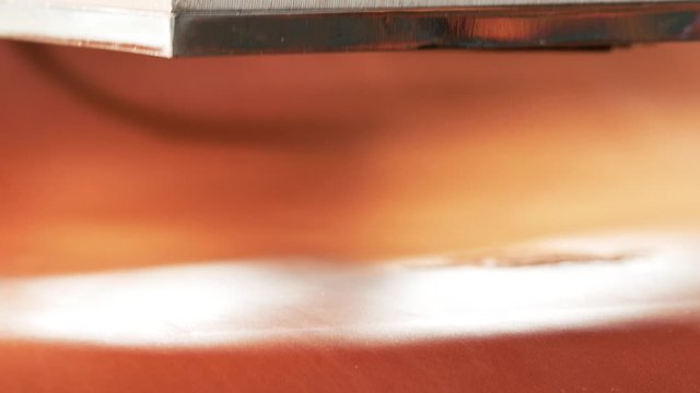 A man branding on leather product. Craftsman uses a hot press to create a logo on a piece of leather 4k