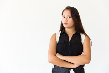 Fototapeta premium Serious confident student girl posing with arms folded. Young Latin woman in casual standing isolated over white background, looking at camera. Studio female portrait concept