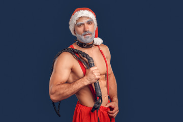 Adult shirtless Santa Claus standing with flogging whip in hand