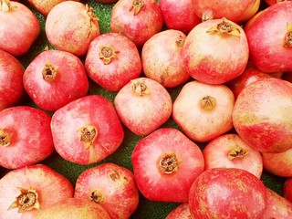 Bright red pomegranates close-up. Ripe juicy pomegranates on counter of bazaar or greengrocer. Selective focus image.