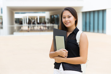 Fototapeta premium Happy young woman with textbooks. Beautiful young female student holding folder with books and smiling at camera. Education concept