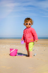 pretty little girl playing on the beach and protected from the sun