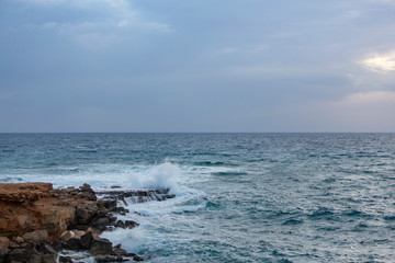 Wave breaking against cliff, Agia Napa, Cyprus.. White spray in the air. Clear turquoise water in foreground.