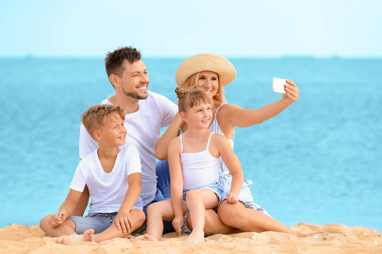 Portrait of happy family taking selfie on sea beach