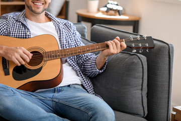 Handsome man playing guitar at home