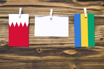 Hanging flags of Bahrain and Gabon attached to rope with clothes pins with copy space on white note...