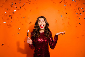 Portrait of excited funky bachelor girl celebrate hen prom party impressed news crazy expression hold champagne wear stunning outfit isolated over orange color background confetti flying falling