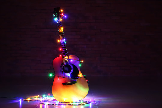 Acoustic Guitar With Christmas Lights Against Dark Background