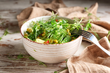 Bowl with fresh vegetable salad on wooden background