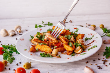 fried potatoes with mushrooms meat onions on a plate wooden white background