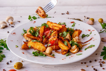 fried potatoes with mushrooms meat onions on a plate wooden white background