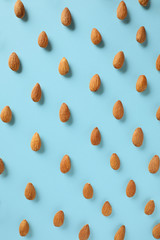 Many tasty almonds on color background