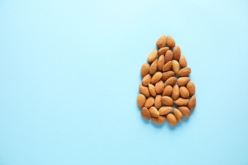 Many tasty almonds on color background