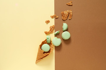 Wafer cone with tasty macarons on color background