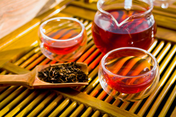 Chinese tea ceremony. Tea in a glass jug and in the cups with a scoop of puerh tea on a bamboo tea desk. 