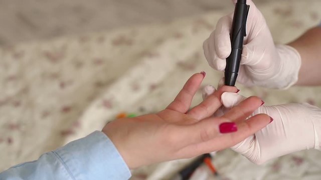 Close-up of a girl piercing his finger with a scarifier to check the level of glucose in the blood. Control diabetes at home with a glucometer. A drop of blood. Blood sampling for glucometer.