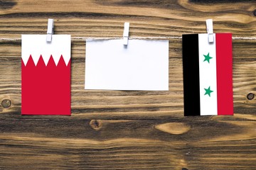 Hanging flags of Bahrain and Syria attached to rope with clothes pins with copy space on white note...