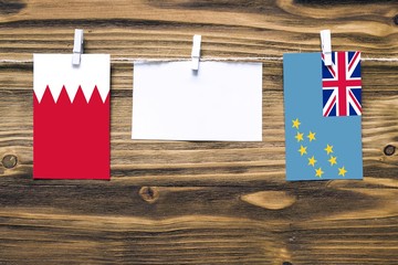 Hanging flags of Bahrain and Tuvalu attached to rope with clothes pins with copy space on white...