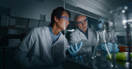 Portrait of two male scientists are making an analysis of the DNA and molecules in the test tubes...