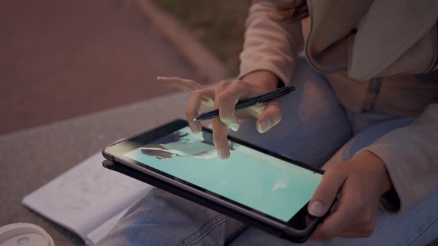A Young Beautiful Woman Entrepreneur Using An Ipad tablet and phone zoom in and drag after work and taking notes Close Up medium shot on a city