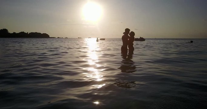 kissing sweethearts under sea sunset of thailand