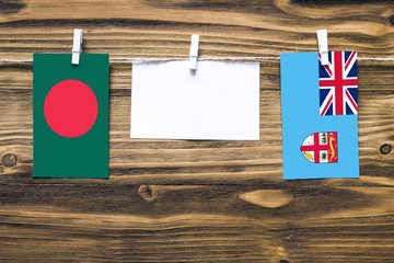 Hanging flags of Bangladesh and Fiji attached to rope with clothes pins with copy space on white...