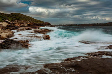 Wave action on coastal rocks with waterfall cascades
