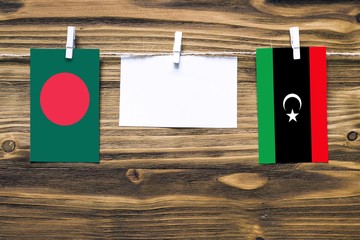 Hanging flags of Bangladesh and Libya attached to rope with clothes pins with copy space on white...