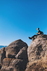 A guy with a backpack sits on a rock in the mountains, drink tea and enjoying view of nature. Nature background. Journey. A trip to the mountains.