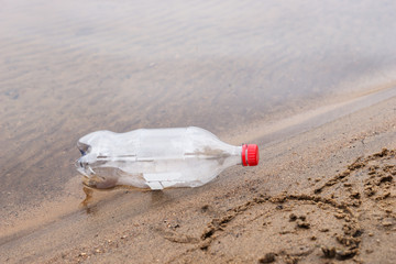 Discarded plastic bottle lies in the sand on a beach