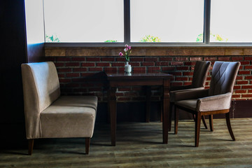 Interior design of restaurant or cafe. Side Photo of wooden table with sofa and two chairs near the table.