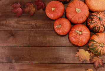 Orange pumpkins and dry fall maple leaves on dark brown wooden table. Welcome Autumn, harvest festival, Halloween, Thanksgiving concept. Top view, copy space
