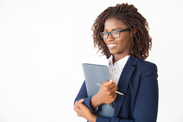 Happy cheerful office assistant in glasses holding documents, looking away, smiling. Young African American business woman posing isolated over white background. Corporate portrait concept