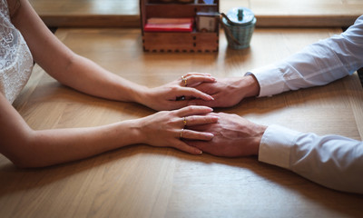 Fototapeta premium Couple in love holding hands in a cafe. Focus on hands