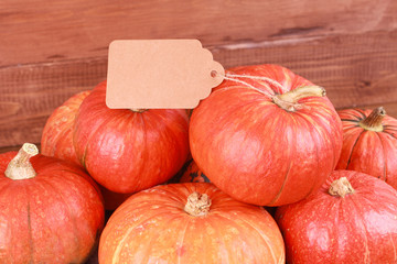 Pumpkins and blank tag on rustic wooden background. Autumn harvest, Halloween, Thanksgiving concept. Fall, holiday, festival, market