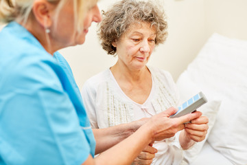 Pflegedienst hilft Seniorin mit der Fernbedienung
