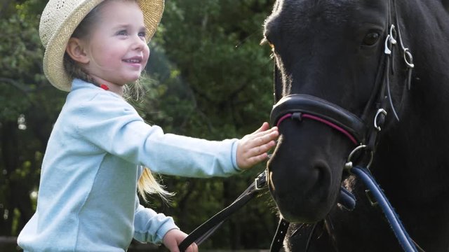 Little girl and black pony in park