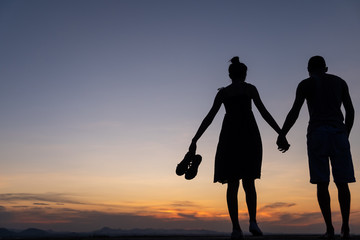 Silhouettes of happy young couple against the sunset sky,walking
